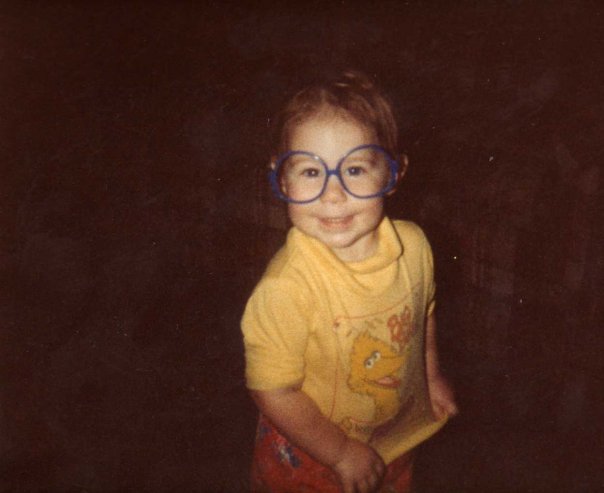 Dominick as a young child, wearing a yellow big bird shirt, and Elton John glasses.
