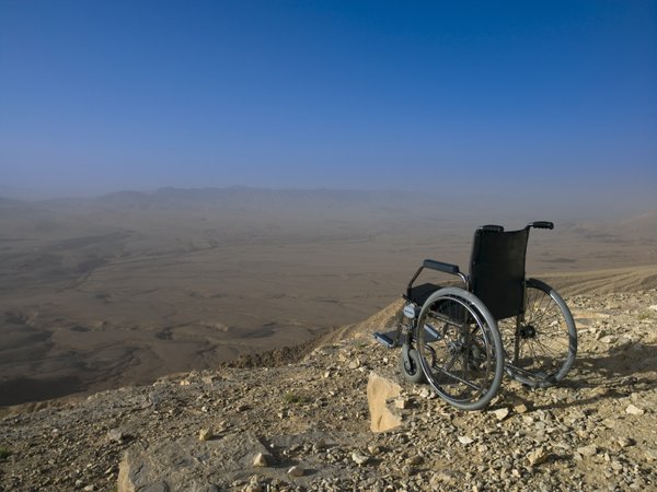 An empty wheelchair, sits on the edge of a cliff...looking out over the vista.