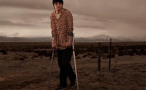 Walter Jr. stands on his crutches looking out with a desert landscape behind him