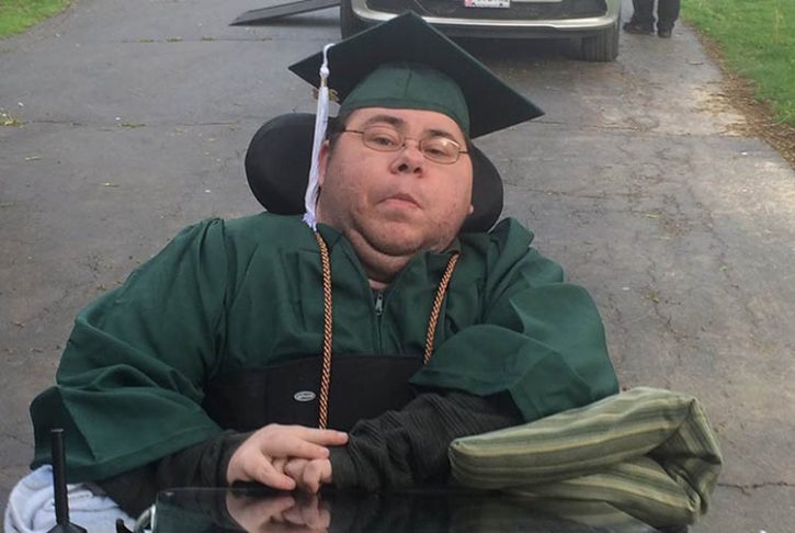 Dominick sits in his cap and gown for graduation, in his driveway.